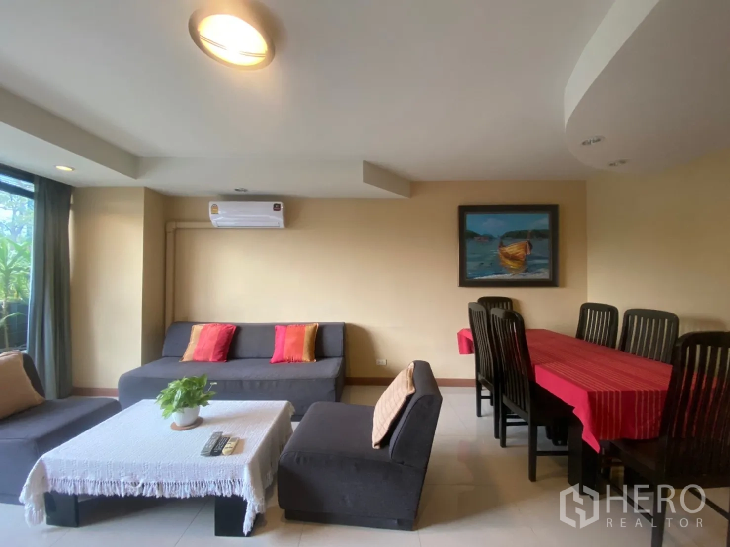 Condominium for rent in Phaya Thai, Bangkok - Bright condo living room with gray sofa, colorful cushions, and a dining table.