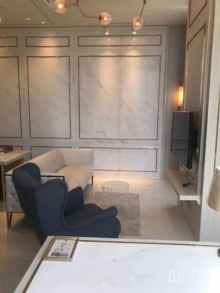 公寓 出租在Bang Rak, Bangkok - 优雅客厅，配沙发、单人椅、壁挂电视与大理石元素。