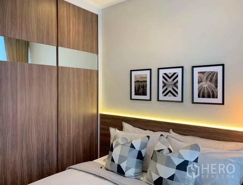 公寓 出售在Ratchathewi, Bangkok - 卧室配镜面推拉衣柜、几何抱枕与柔和灯光。