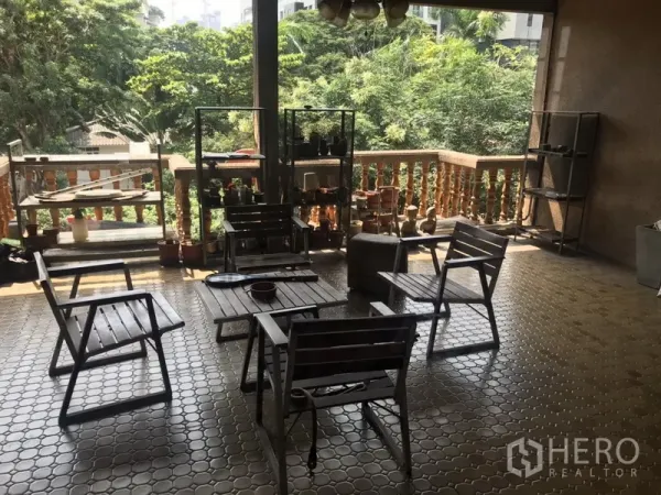 Home Office for rent in Khlong Toei, Bangkok - Covered terrace with tiled floor, wooden seating and leafy treetop views.