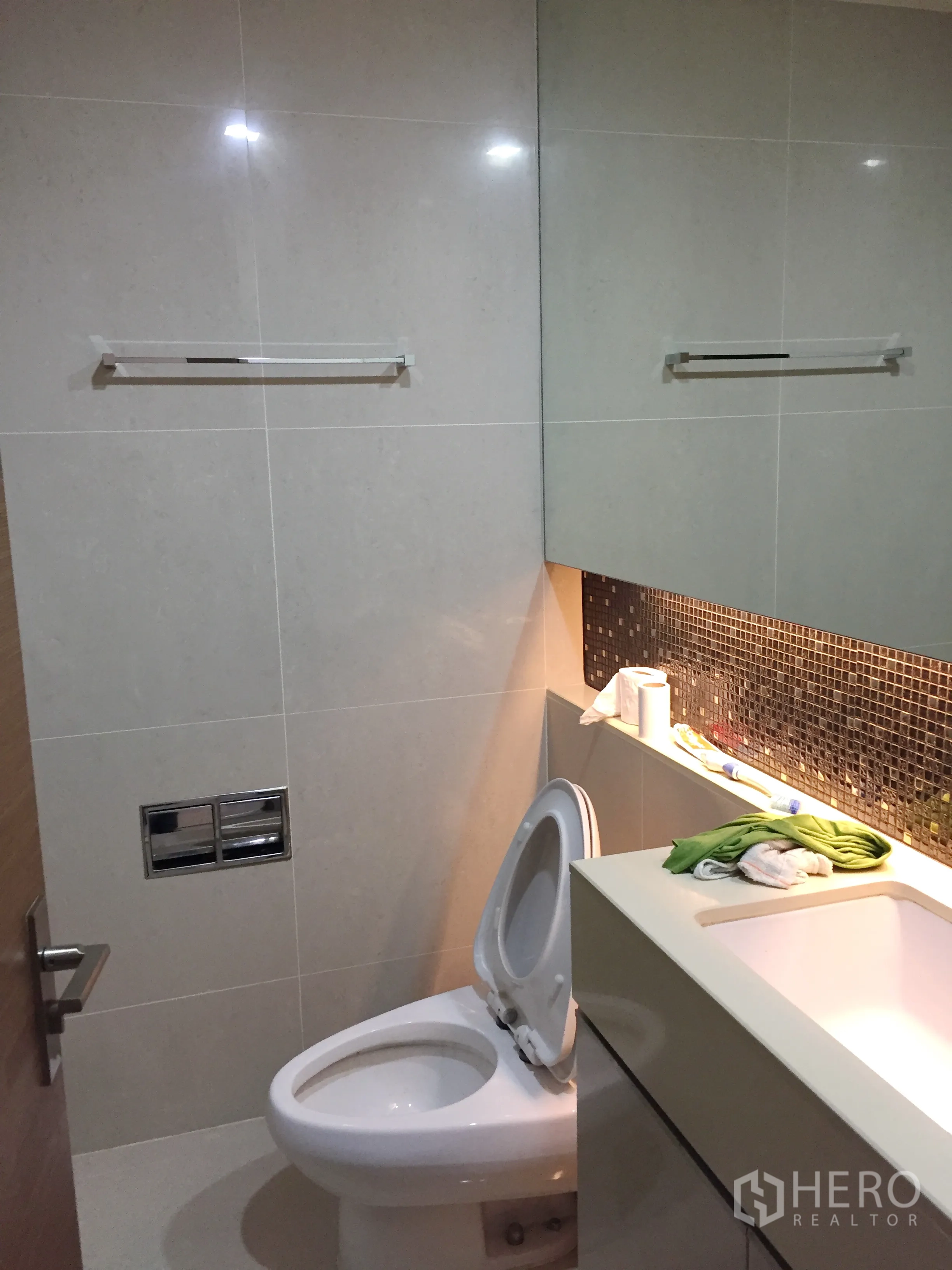 Condominium for rent in Bang Rak, Bangkok - Modern bathroom with vanity, mosaic backsplash and toilet in a clean tiled finish.
