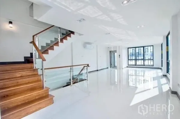 Home Office for rent in Don Mueang, Bangkok - Open-plan level featuring a wooden staircase with glass balustrade and wide windows.