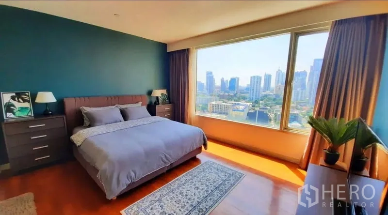 Condominium for rent in Watthana, Bangkok - Primary bedroom with king bed and panoramic city skyline through a wall‑to‑wall window.