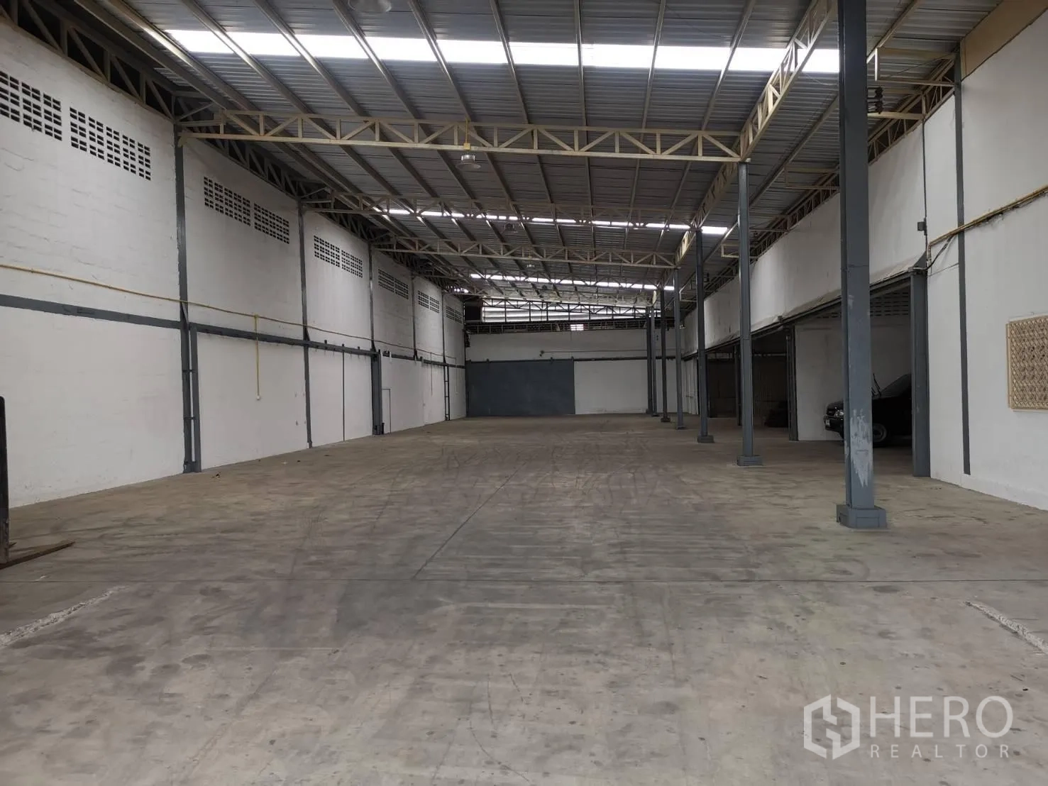 Warehouse for rent in Suan Luang, Bangkok - Spacious clear-span warehouse hall with support columns and wide concrete loading space.