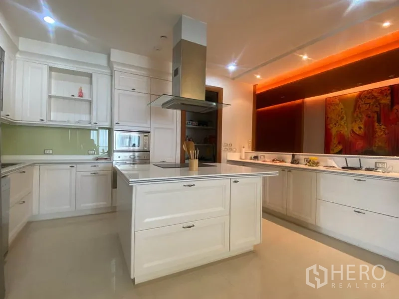 Condominium for rent in Sathon, Bangkok - Bright white kitchen with island, built-in oven, range hood and ambient lighting.