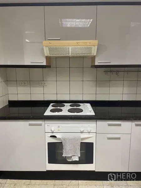 公寓 出租在Pathum Wan, Bangkok - 厨房烹饪区，电炉、烤箱、瓷砖挡板与抽油烟机。