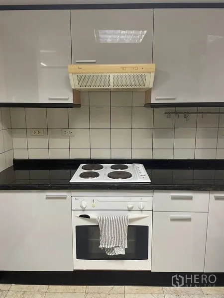 公寓 出租在Pathum Wan, Bangkok - 厨房烹饪区，电炉、烤箱、瓷砖挡板与抽油烟机。