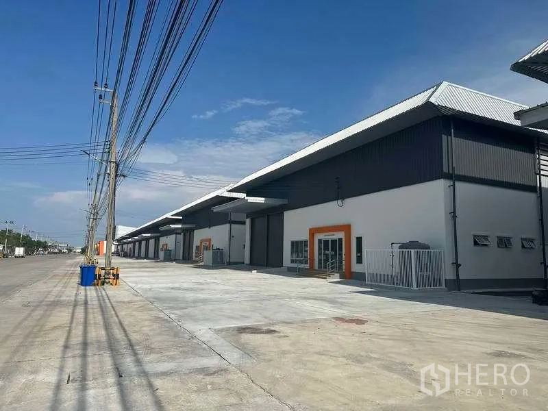 Factory for rent in Bang Sao Thong, Samut Prakan - Row of new factory units along a wide road with loading aprons and overhead power lines.