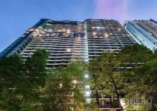 Condominium for sale in Phaya Thai, Bangkok - Modern high-rise condominium exterior illuminated at dusk, viewed from below.