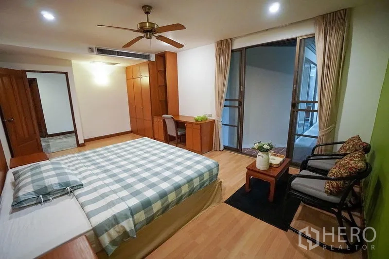 Apartment for rent in Watthana, Bangkok - Bedroom with study area, wardrobes and access to a covered balcony.