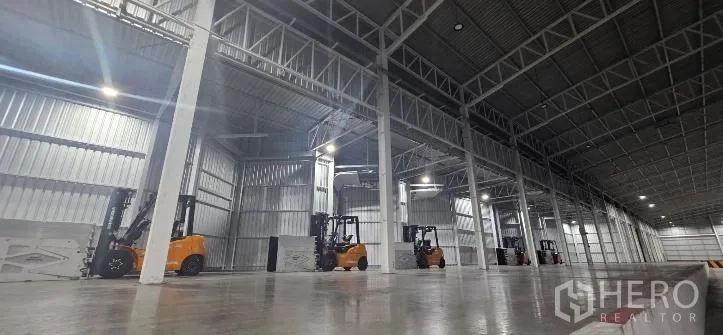 โรงงาน for rent in Si Racha, Chon Buri - ภายในโกดังขนาดใหญ่มีเสาเหล็ก รถโฟล์คลิฟต์ และพื้นคอนกรีตขัดมัน.