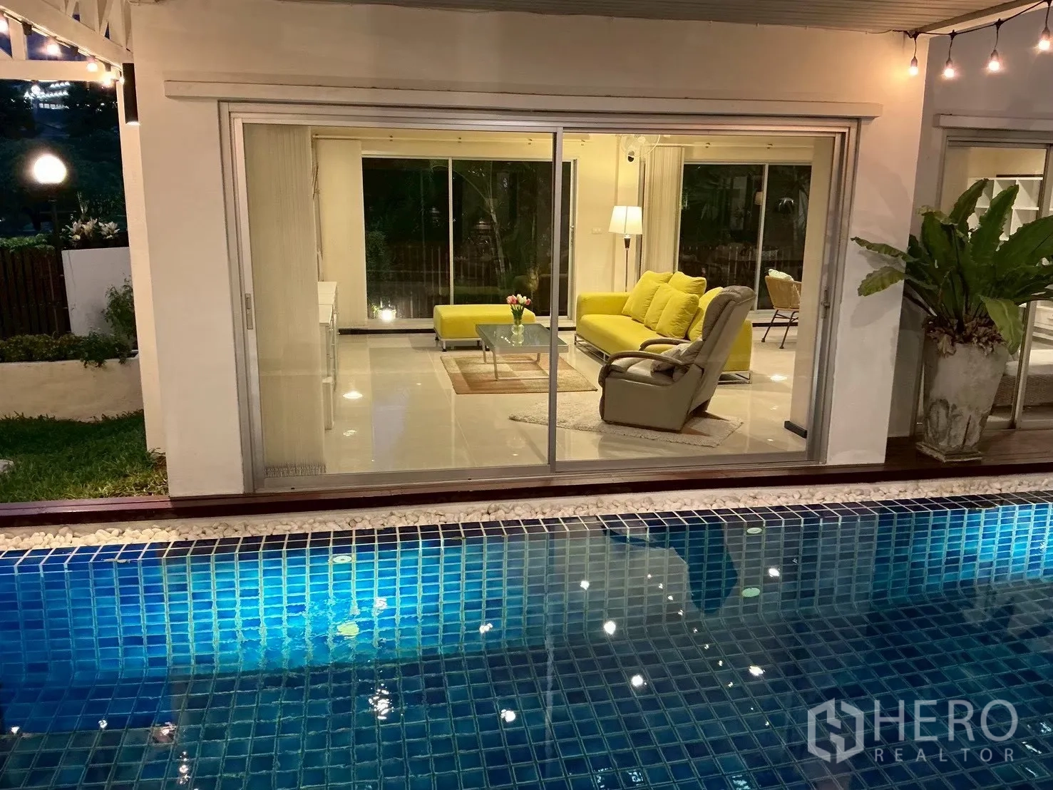 独栋房屋 for sale in Suan Luang, Bangkok - 夜景中从泳池望见配黄色沙发的客厅。
