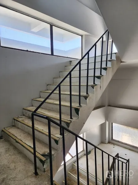 Factory for rent or sale in Khlong Toei, Bangkok - Concrete staircase with black metal handrail and large windows in the stair core.