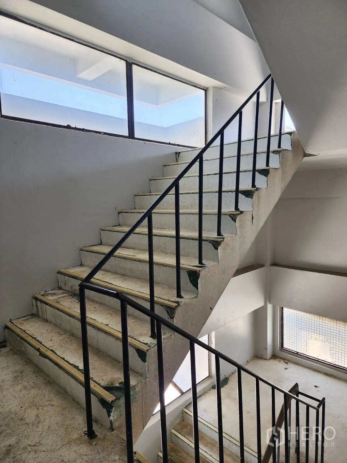 Factory for rent or sale in Khlong Toei, Bangkok - Concrete staircase with black metal handrail and large windows in the stair core.