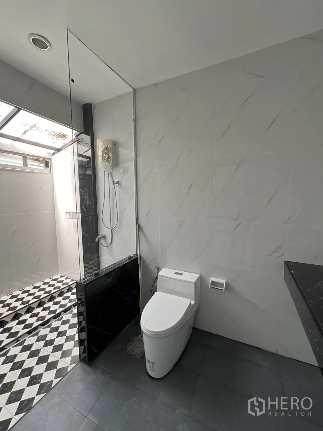 联排别墅 for rent in Watthana, Bangkok - 明亮卫浴，坐便与抬高淋浴区，黑白菱格地砖。