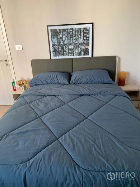 Townhouse for rent in Suan Luang, Bangkok - Guest bedroom featuring a gray upholstered bed with blue bedding and a side table.