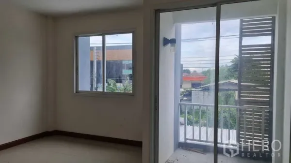 Townhouse for  in Lam Luk Ka, Pathum Thani - Bedroom with window and sliding glass door opening to a small balcony with neighborhood view.