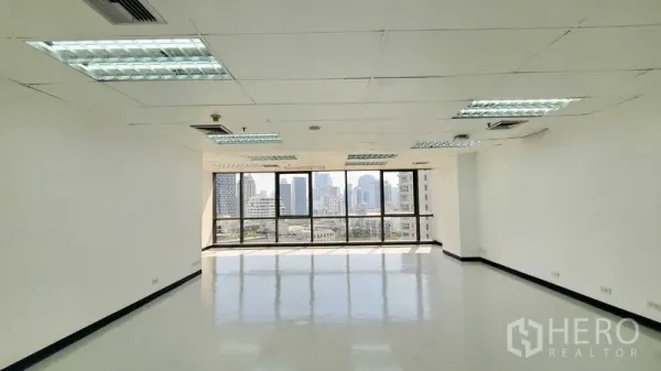 办公空间 出租在Watthana, Bangkok - 明亮的空置办公室，整面窗户可赏曼谷天际线，吊顶与荧光灯清晰可见。