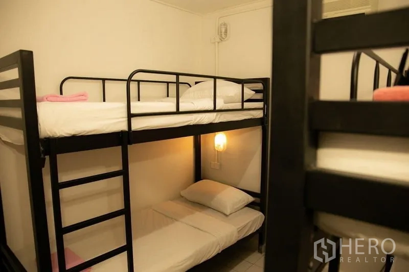 Shophouse for rent in Khlong Toei, Bangkok - Cozy bunk room with black metal bunks and a warm wall sconce.
