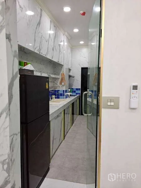 公寓 出租在Khlong Toei, Bangkok - 狭长型厨房，带大理石橱柜、玻璃门和高冰箱，灯光充足。