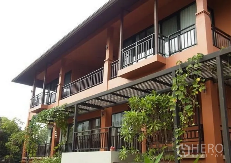 Detached House for rent in Khlong Toei, Bangkok - Two-storey terracotta villa facade with balconies, pergola and lush plants.