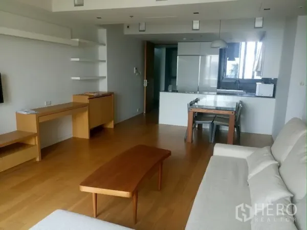 Condominium for rent in Sathon, Bangkok - Spacious living area facing an open kitchen with dining set and built-in shelves.
