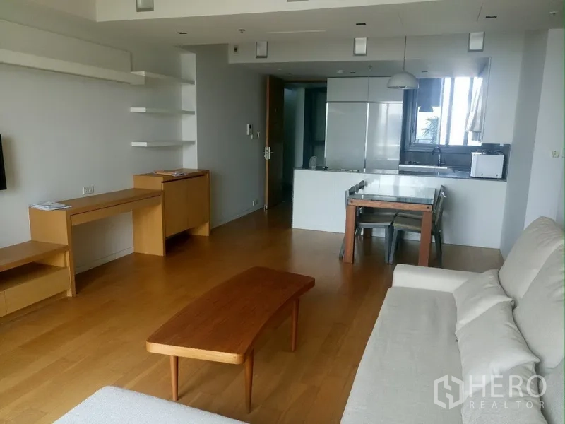 Condominium for rent in Sathon, Bangkok - Spacious living area facing an open kitchen with dining set and built-in shelves.