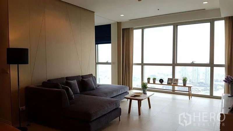 公寓 出租在Khlong San, Bangkok - 宽敞客厅，转角沙发与落地窗俯瞰城市天际线