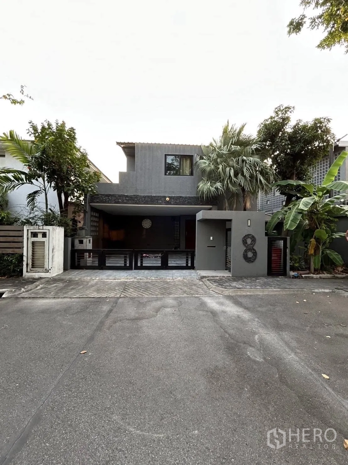 Detached House for rent or sale in Wang Thonglang, Bangkok - Modern two-storey detached house facade with gated carport and tropical trees in Wang Thonglang, Bangkok.