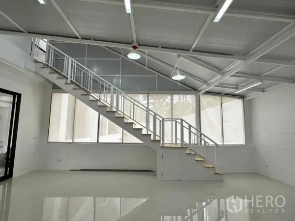 Office Space for rent or sale in Khlong Toei, Bangkok - Loft-style office with high ceiling, large windows and a long internal staircase to a mezzanine.