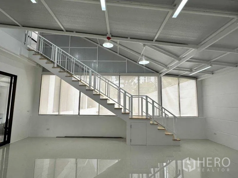 Office Space for rent or sale in Khlong Toei, Bangkok - Loft-style office with high ceiling, large windows and a long internal staircase to a mezzanine.