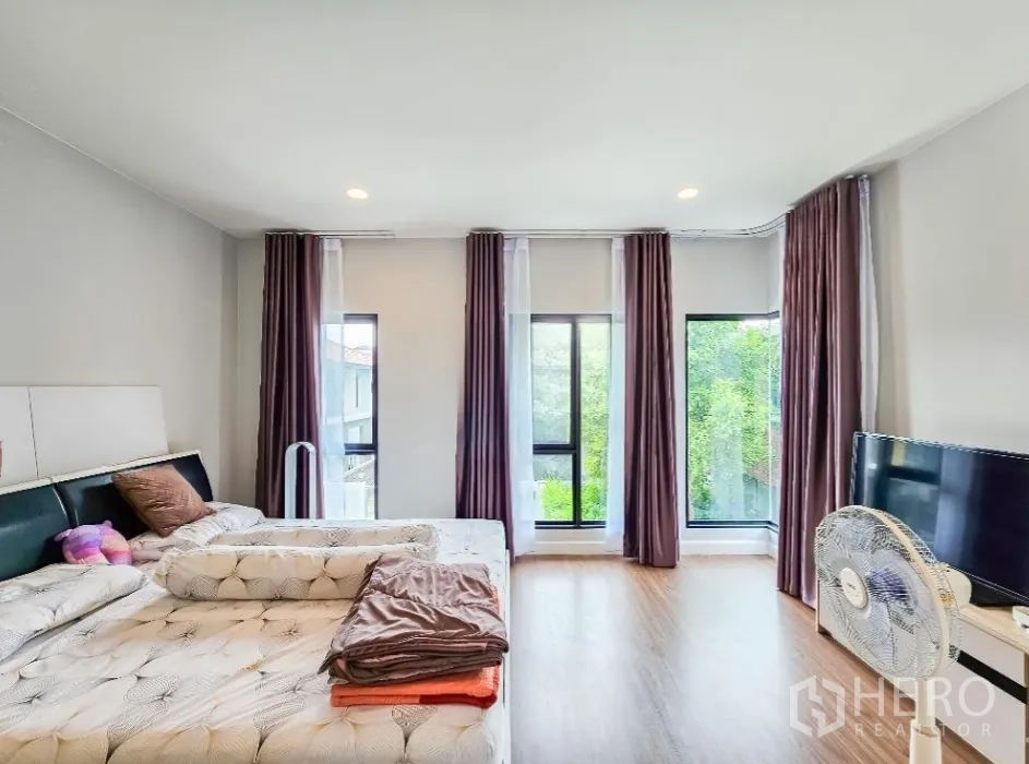 Detached House for sale in Lam Luk Ka, Pathum Thani - Master bedroom view toward tall windows with greenery outside.