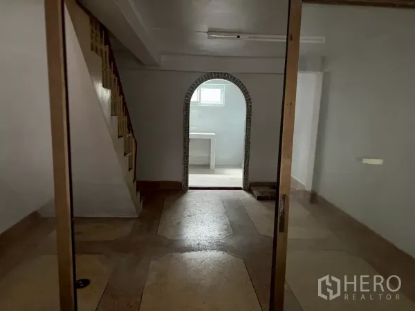 Shophouse for rent in Khlong Toei, Bangkok - Interior view to an arched rear room with staircase and glass doors on the ground floor.