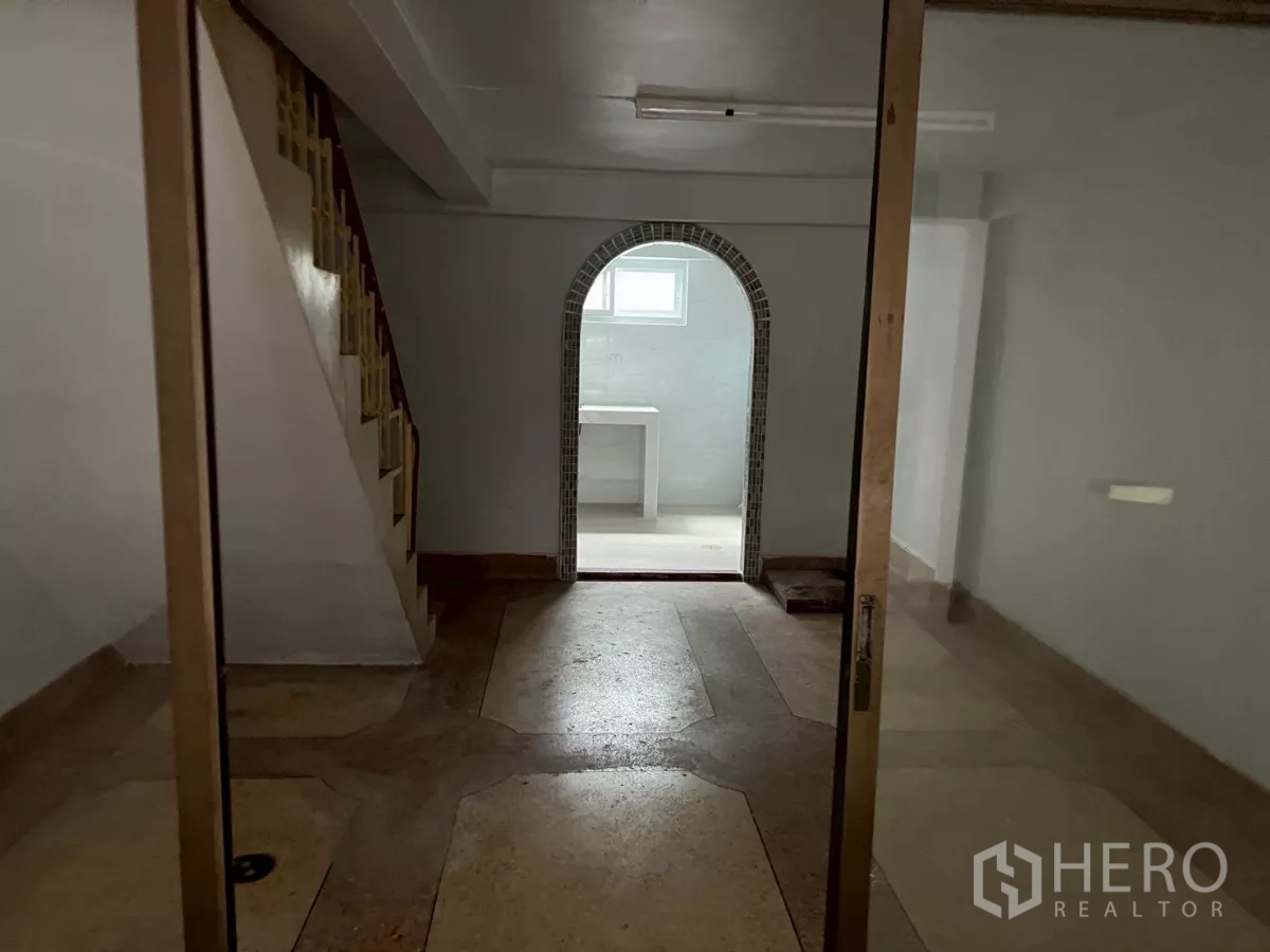 Shophouse for rent in Khlong Toei, Bangkok - Interior view to an arched rear room with staircase and glass doors on the ground floor.