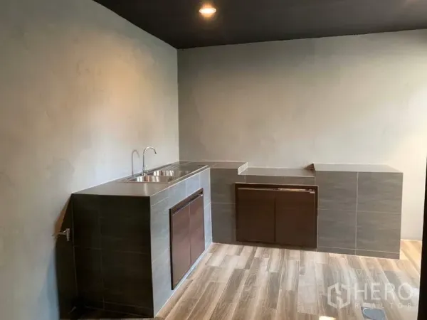 Townhouse for rent in Bang Kapi, Bangkok - Minimalist Thai kitchen with tiled counters, double sink and wood-look flooring.