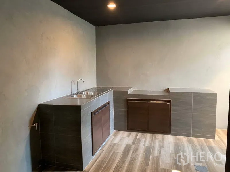 Townhouse for rent in Bang Kapi, Bangkok - Minimalist Thai kitchen with tiled counters, double sink and wood-look flooring.