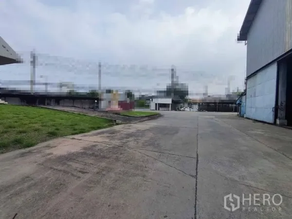 Warehouse for rent in Samut Sakhon - Spacious concrete loading yard and driveway beside warehouse buildings in Om Noi.