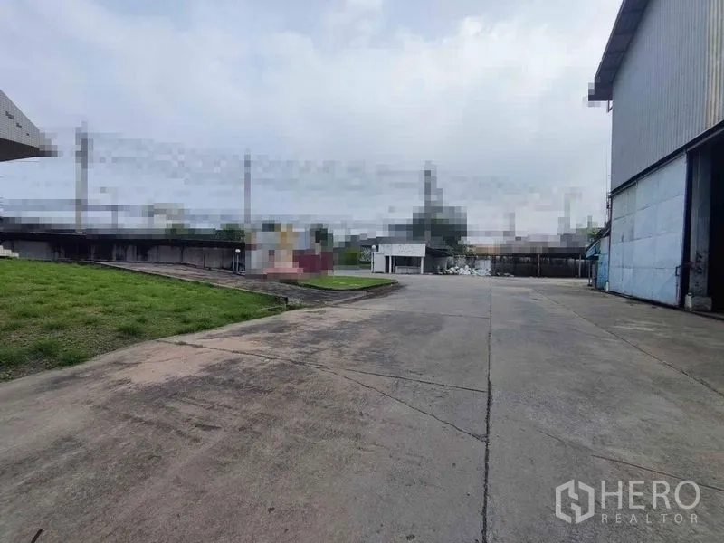 Warehouse for rent in Samut Sakhon - Spacious concrete loading yard and driveway beside warehouse buildings in Om Noi.