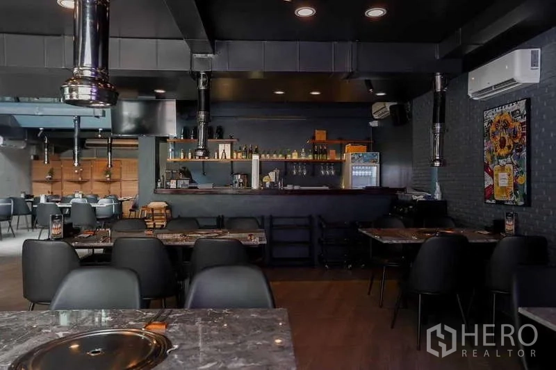 Detached House for rent in Watthana, Bangkok - Open-plan dining space with bar counter, marble tables, ceiling ducting and recessed lighting.