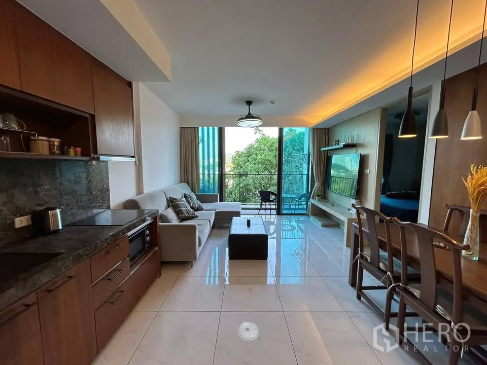 公寓 出租在Watthana, Bangkok - 开放式客厅，带厨房、沙发、餐桌和面向绿景的阳台
