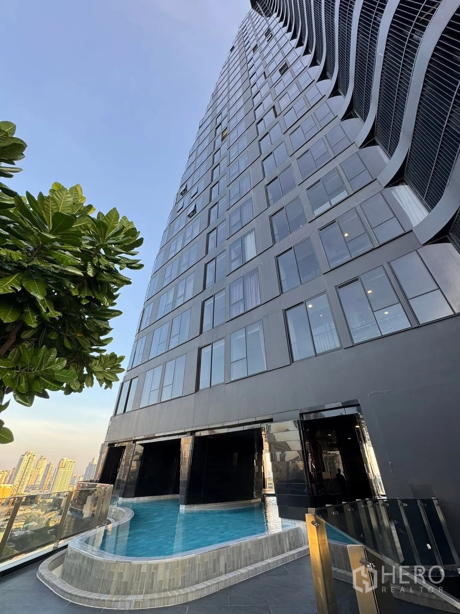 Condominium for rent in Khlong Toei, Bangkok - Modern high-rise condominium exterior with curved facade and pool deck.