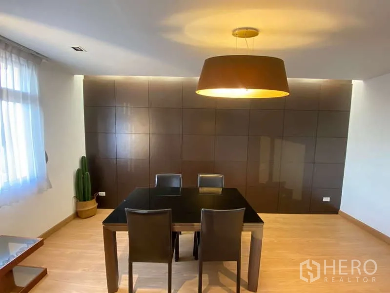 Condominium for rent in Khlong Toei, Bangkok - Dining area with a black four-seat table, pendant light, dark feature wall and sheer-curtained window.