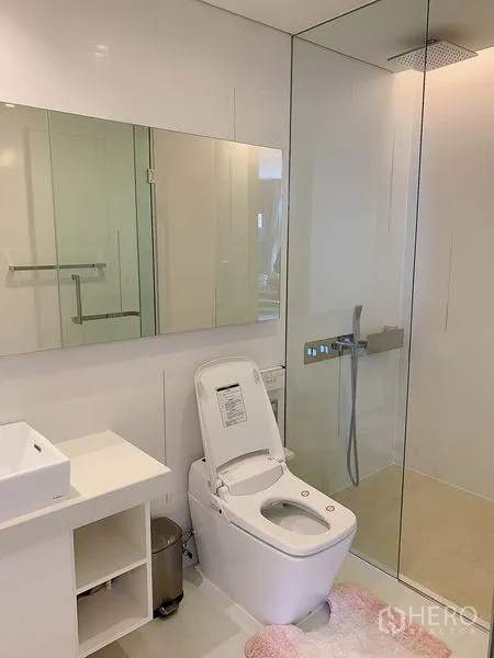 Condominium for sale - Rain shower enclosure and smart toilet in a sleek white bathroom.