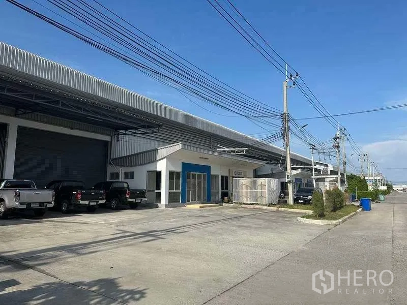 工厂 出租在Bang Sao Thong, Samut Prakan - 工业园内一排厂房，宽阔道路与停车位。