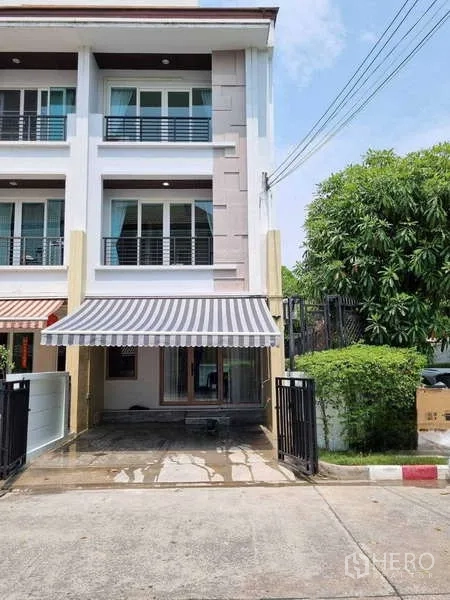 联排别墅 出租在Wang Thonglang, Bangkok - 三层端头联排外观，条纹遮阳篷与带门车位。