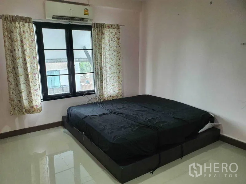 Townhouse for sale in Khlong Toei, Bangkok - Primary bedroom with black bed, air conditioner, and curtained window.