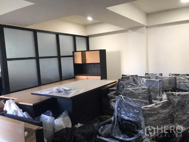 Office Space for rent in Khlong Toei, Bangkok - Open-plan office featuring frosted glass partitions, storage cabinets and stacked new chairs.
