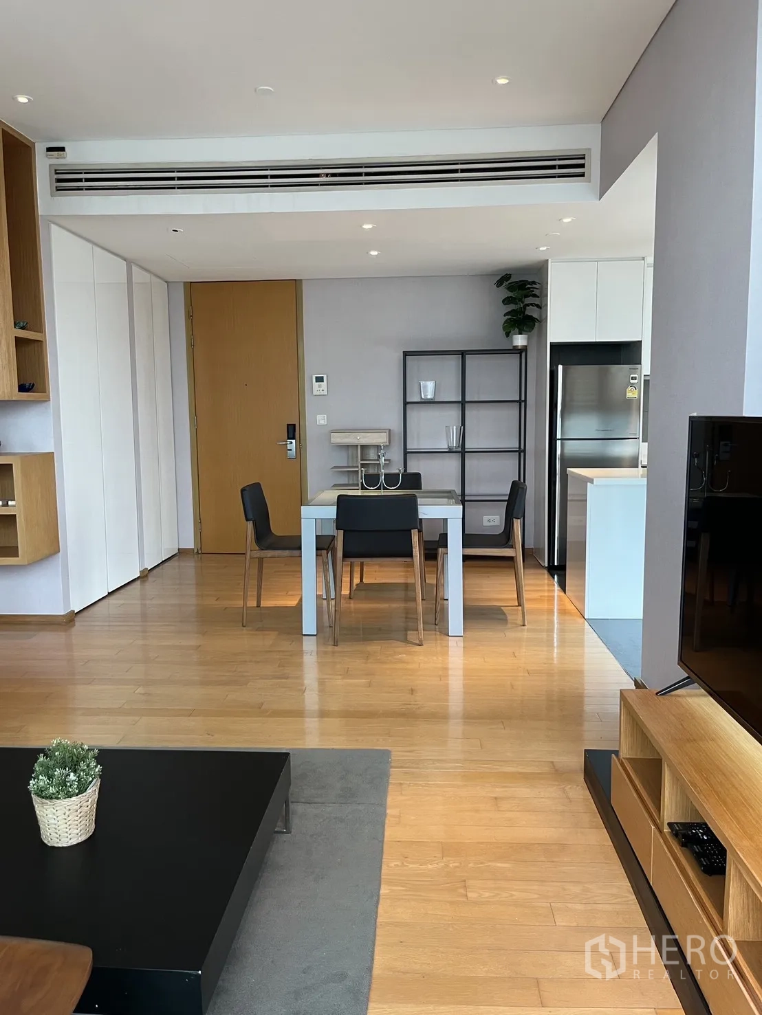 Condominium for rent in Watthana, Bangkok - Living room overview showing dining table, kitchen, and built-in storage.