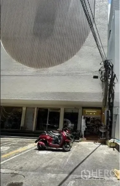 Retail Space for rent in Watthana, Bangkok - Building forecourt with marked parking and a red scooter in front of retail units.