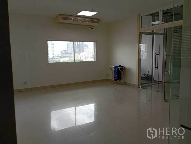 Office Space for rent in Khlong Toei, Bangkok - Corner office with city view window, glass partitions, tiled flooring and built-in air conditioning.
